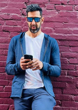 alex from navas lab wearing blue hoodie and white tee in front of red wall