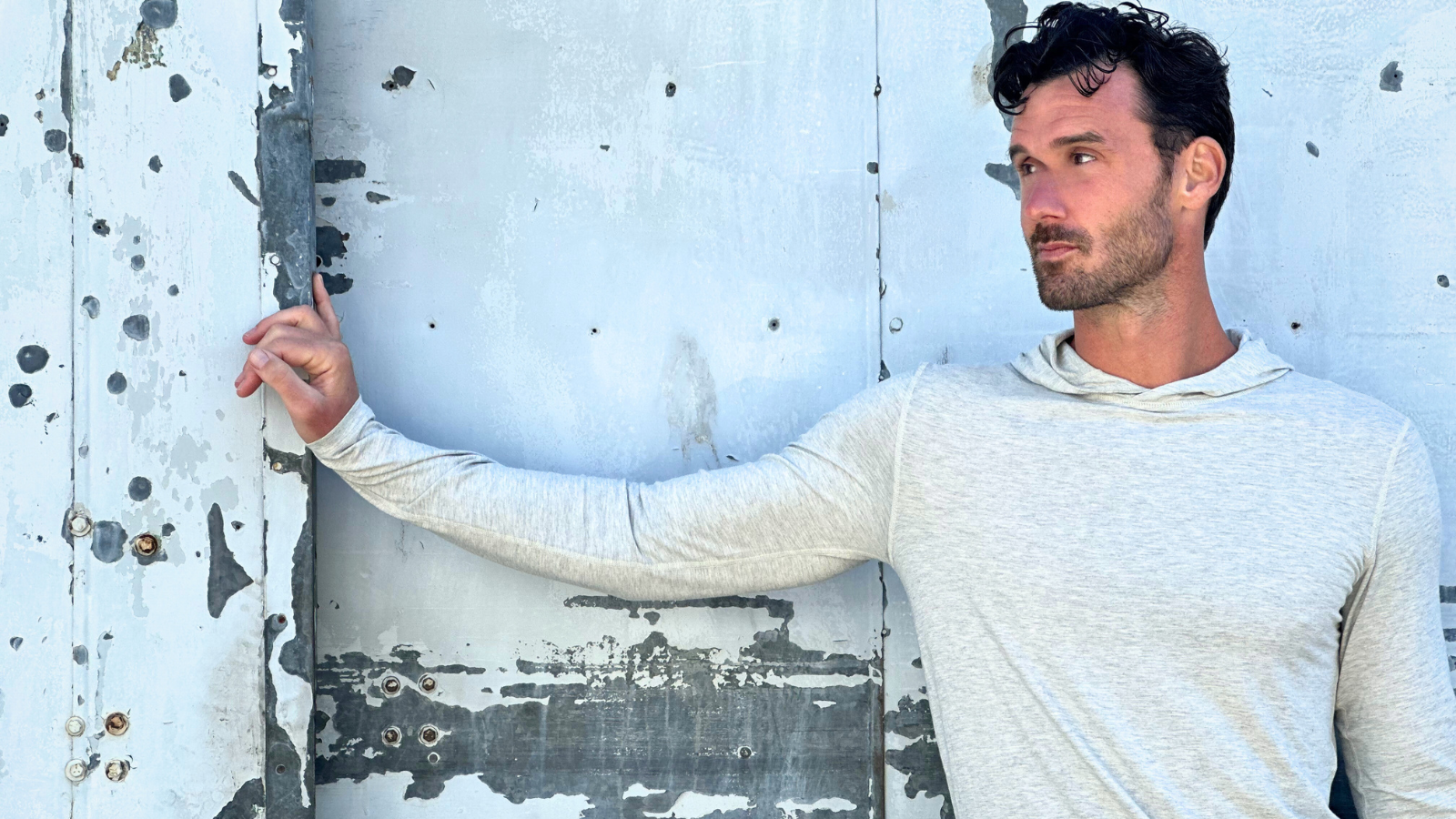 tall guy with brown hair wearing grey navas lab hoodie in front of grey distressed wall