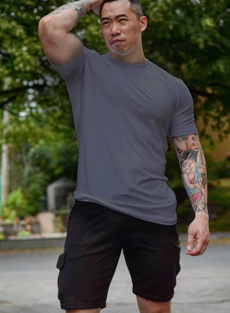 tall muscly man wearing grey navas lab tee and black shorts at park