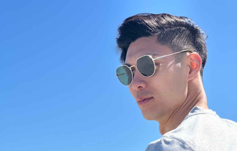 tall guy with sunglasses and grey shirt in front of blue sky